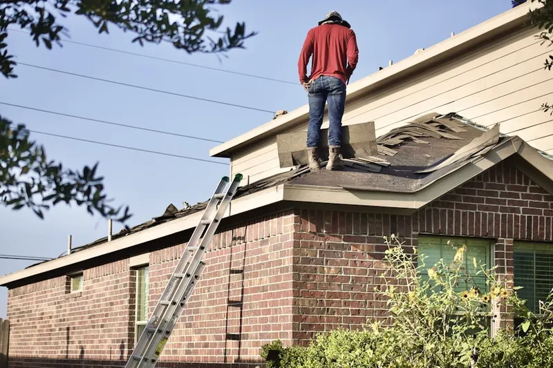 Professional roofer working on a residential roof in Upper Falls